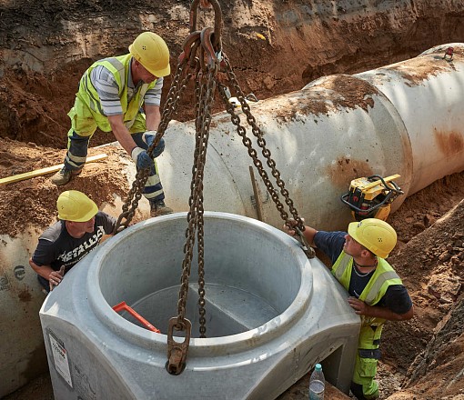 Kanalrohr wird in Baugrube herabgelassen