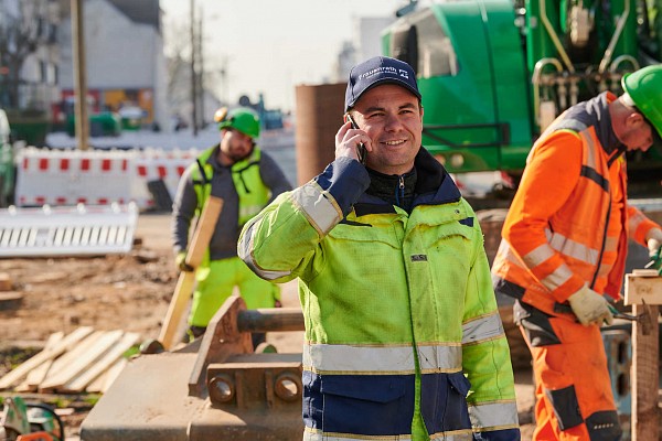 Bauarbeiter auf Baustelle mit Telefon am Ohr